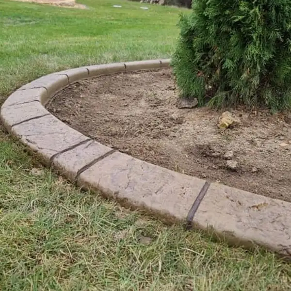 Concrete curb circling a landscape bed with an evergreen shrub
