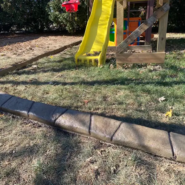 Close-up of a concrete curb edging a backyard play area