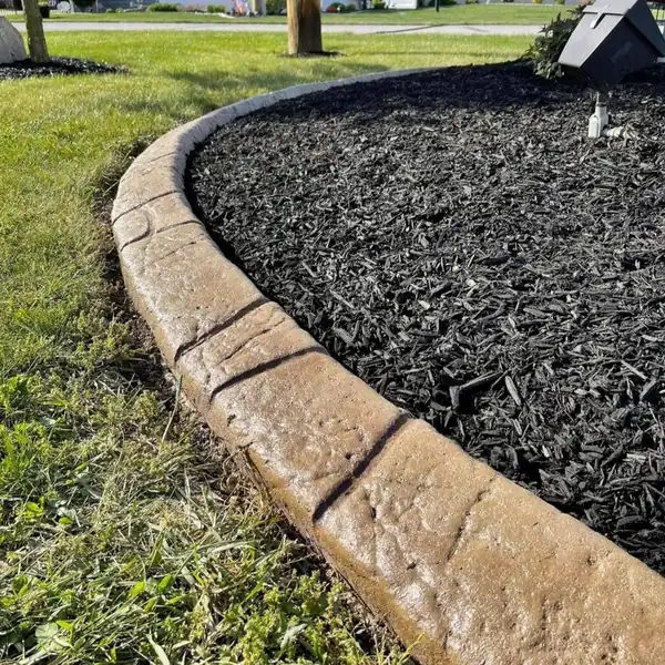 Close-up of stamped concrete curb edging a black mulch bed